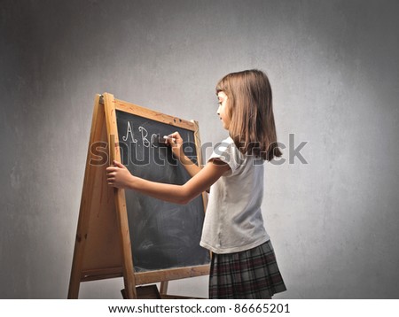Little girl writing the alphabet on a blackboard