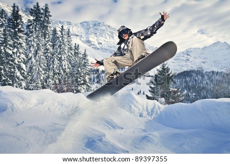 Young man jumping with a snowboard in the mountains