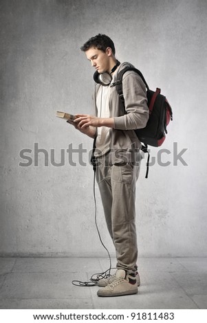 Young student wearing headphones and holding a book