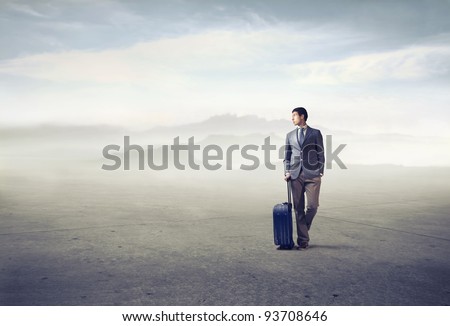 Young african man holding a suitcase in a desert