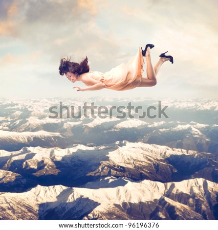 Laughing beautiful woman flying over the mountains