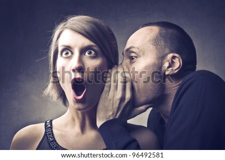 Man telling an astonished woman some secrets
