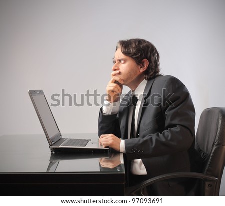 Businessman with doubtful expression in front of a laptop