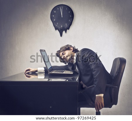 Tired businessman sleeping on his laptop with clock in the background