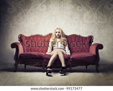 Rich elegant woman sitting on a velvet antique sofa