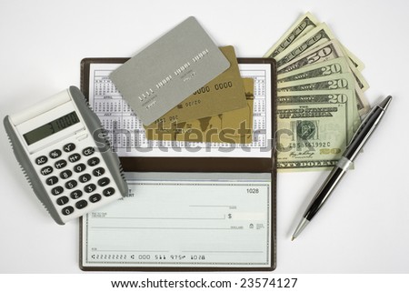 Checkbook open with blank check showing along with a calculator, pen, cash, and credit cards.