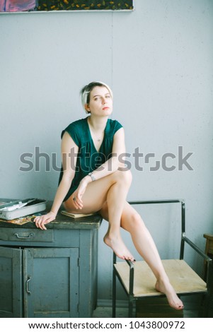 Young Caucasian Blond Girl With A Short Haircut And Green Shirt With Naked Legs Indoor Young Caucasian Blond Girl With A Short Haircut And Green Shirt With Naked Legs Indoor