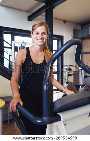 Gym, a beautiful young blonde woman using a step machine during a workout. In sportswear gym smiling looking at the viewer