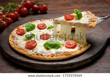 Hot pizza  and slice with melting cheese pull.