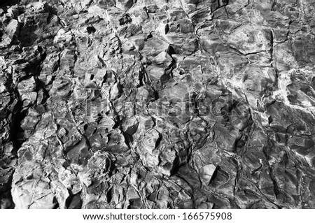 Black and white image of the surface designated rock in the foreground, cracked, chipped, deepening