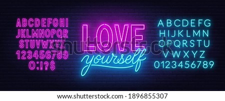 Love yourself neon inspirational quote on a brick wall.