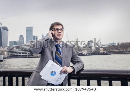 The businessman on the street, background skyscrapers London. speaks on the smartphone