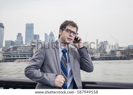 The businessman on the street, background skyscrapers London.  speaks on the smartphone