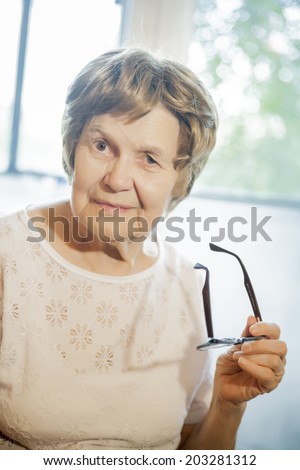 the old woman smiling and holding glasses
