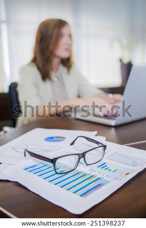 financial chart near dollars seen by unfocused glasses ( colleagues meeting to discuss their future financial plans only silhouettes being viewed )  silhouette of a girl working at the computer