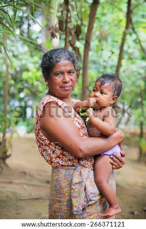 TRINCOMALEE, SRI LANKA  - February 3: old Asian woman with a small child in her arms on February 3, 2013 in Trincomalee, Sri Lanka