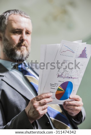 businessman with big beard holding financial statements in the office