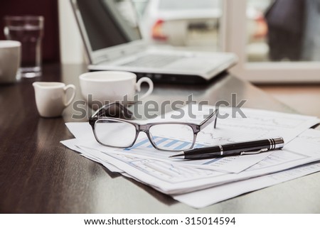 freelancer needs workstation with luxury accessories open laptop computer and coffee, glasses, business graphics in a coffee shop