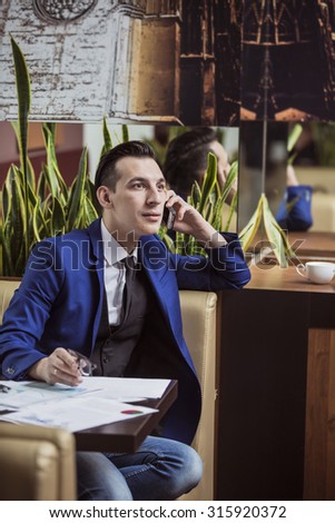 young businessman talking on the phone happily discussing the case in a coffee shop