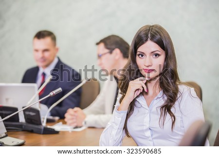 close up of a serious businesswoman with colleagues in meeting in background at the office