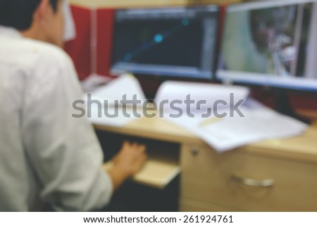 blurred of hardworking man at his desk working on the computer screens.