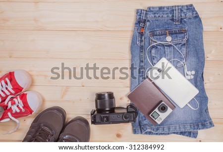 Still life of  denim shorts, mobile phone, earphones,action cam,compact camera,shoes on wood background