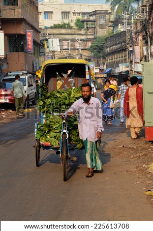 KOLKATA (CALCUTTA), WEST BENGAL, INDIA, OCTOBER 02, 2014: Man transporting vegetables on a cycle rickshaw in the morning