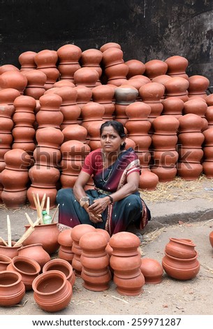 TRIVANDRUM, KERALA, INDIA, MARCH 04, 2015: Woman Entrepreneur.  Woman empowerment. Woman power. Bread winner. A young woman sells pots in the morning during Attukal ponkala festival.
