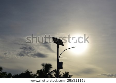 Street light powered by solar energy. Solar panel and LED lamp. Silhouette of a street lamp against the setting sun.
