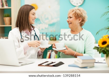 Smiling doctor drinking tea and talking to her patient.