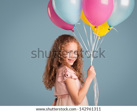 Portrait of cute smiling girl holding a bunch of balloons.