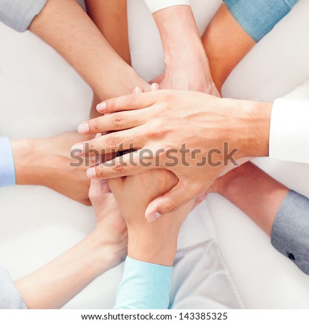 A group of people showing their unity by putting their hands one on top of the other.
