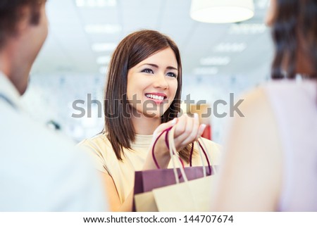 A shop assistant giving the clothes they have bought to the customers.