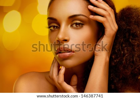 Portrait of a beautiful young African woman gently touching her face.
