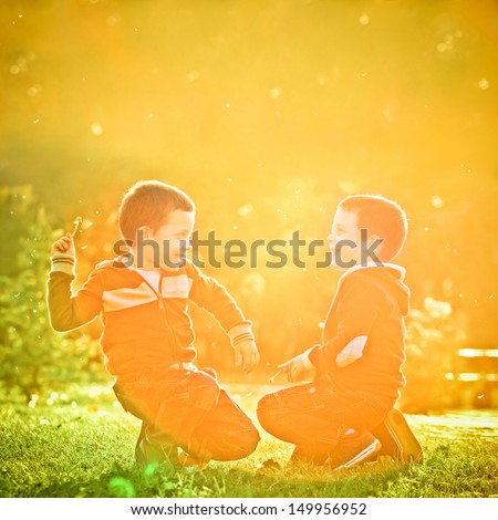 Little twin brothers having fun in the park in a beautiful sunset.