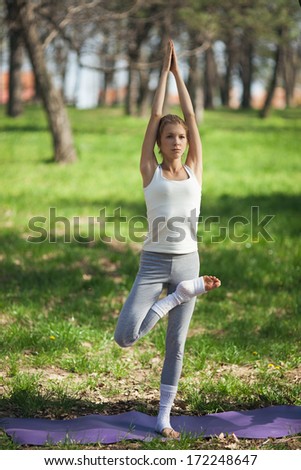 Young Caucasian woman standing in the Tree yoga pose outdoors.