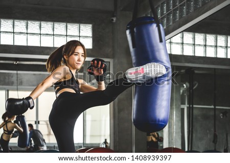 Young asian athlete woman with boxing gloves doing kick boxing training in sport gym