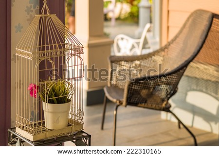 interior of vintage cage with flower vase and wicket chair in home