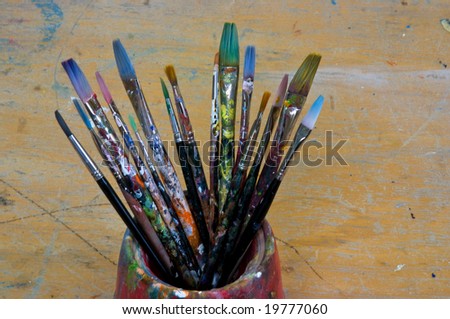 Several artist brushes in a pot, all have been used many times