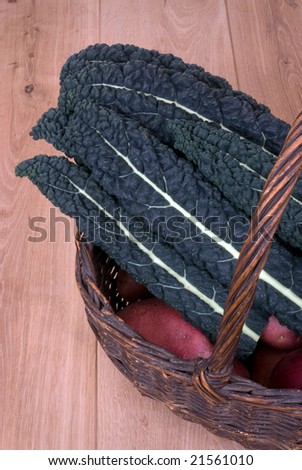 Several leaves of the vegatable Cavalo-nero (black kale) in a basket on a wooden floor