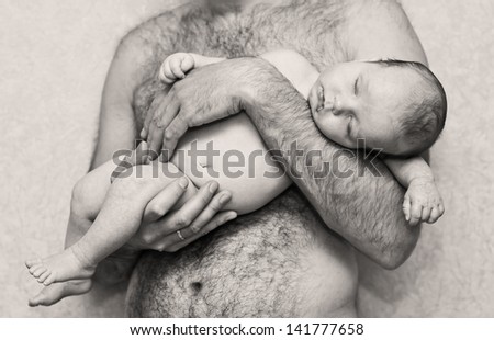 baby sleeps in his father\'s arms