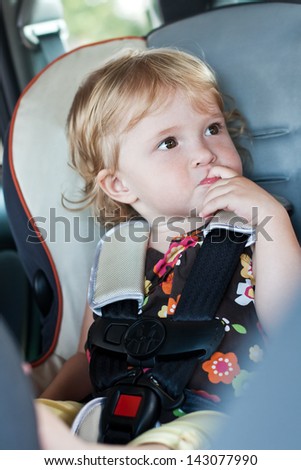 Cute baby his finger in his mouth sitting in the car seat