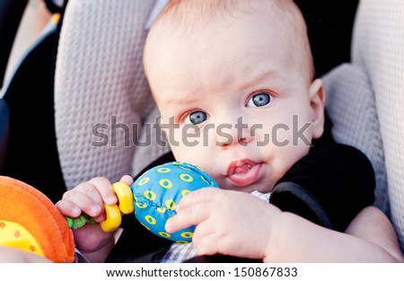 baby boy in car seat holding a toy in his hand