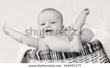 happy baby boy lying in basket on a white background ( black and white )