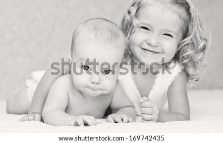 happy little sister hugging her brother lying ( black and white )