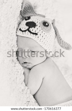 cute newborn baby sleeps in a knitted hat dogs ( black and white )
