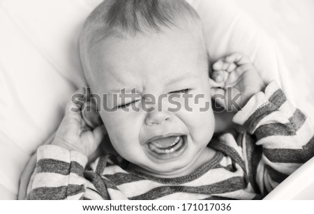 cute little boy crying and holding his ear on a white background ( black and white  )