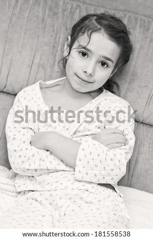 cute little girl in pajamas sitting on the couch ( black and white )
