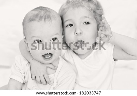 adorable happy little boy dabbles with her older sister on a white background ( black and white )