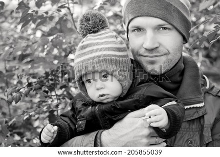 Happy father and his baby son having fun in the park (focus on the boy) ( black and white )